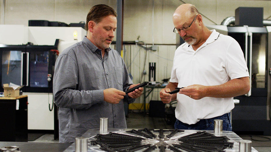 Cimatron で設計および製造されたプラスチック射出成形金型で生産された最終パーツを検査する社長兼 CEO の Ted Stender 氏とシニア金型設計者の Dave VanDeLaare 氏